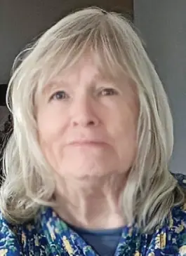 Older woman with long gray hair smiling.