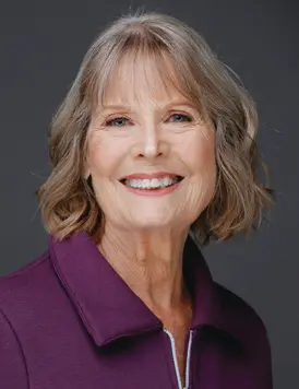 Smiling woman with short hair, wearing purple.