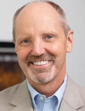 Smiling man in a gray suit jacket.