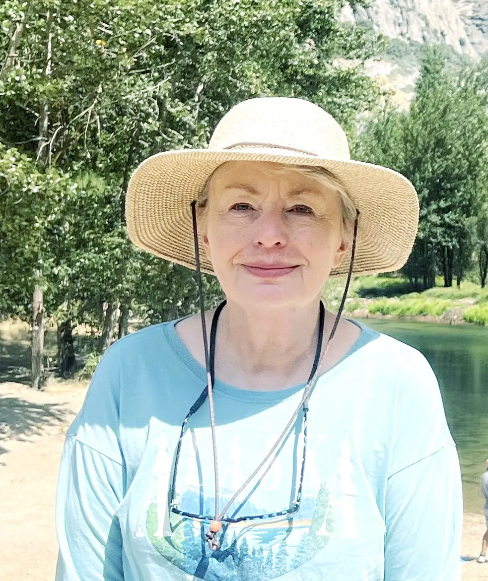 Woman wearing hat, smiling in outdoor setting.